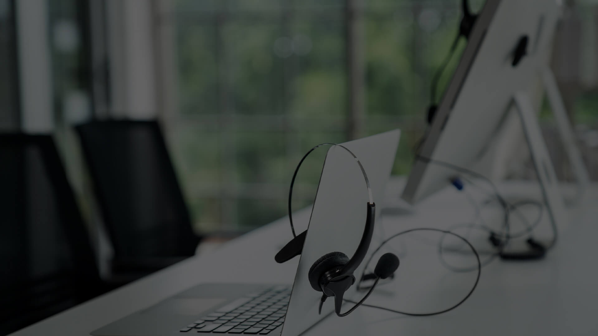 Artistic representation of a modern enterprise help desk work environment. The image features an unoccupied headset resting beside a laptop on a sleek desk, suggesting readiness for customer support services.