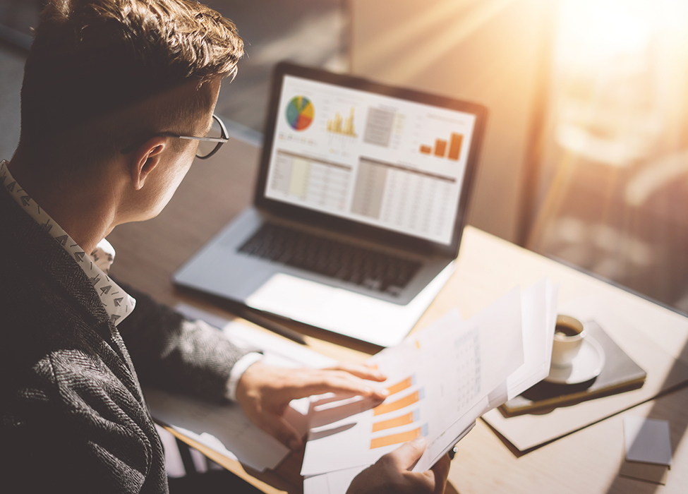 Transaction Management | Image of person working on laptop and comparing numbers on a paper to numbers on screen