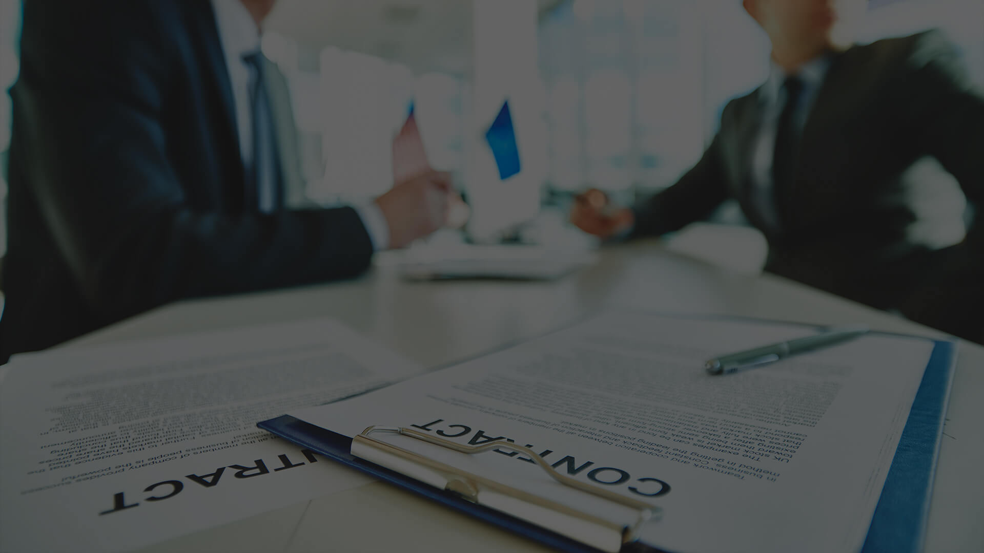 The Intersection of Technology and Business Legal Services Two business professionals in a meeting with a focus on a contract document on the table, highlighting the importance of business legal services in formal agreements.