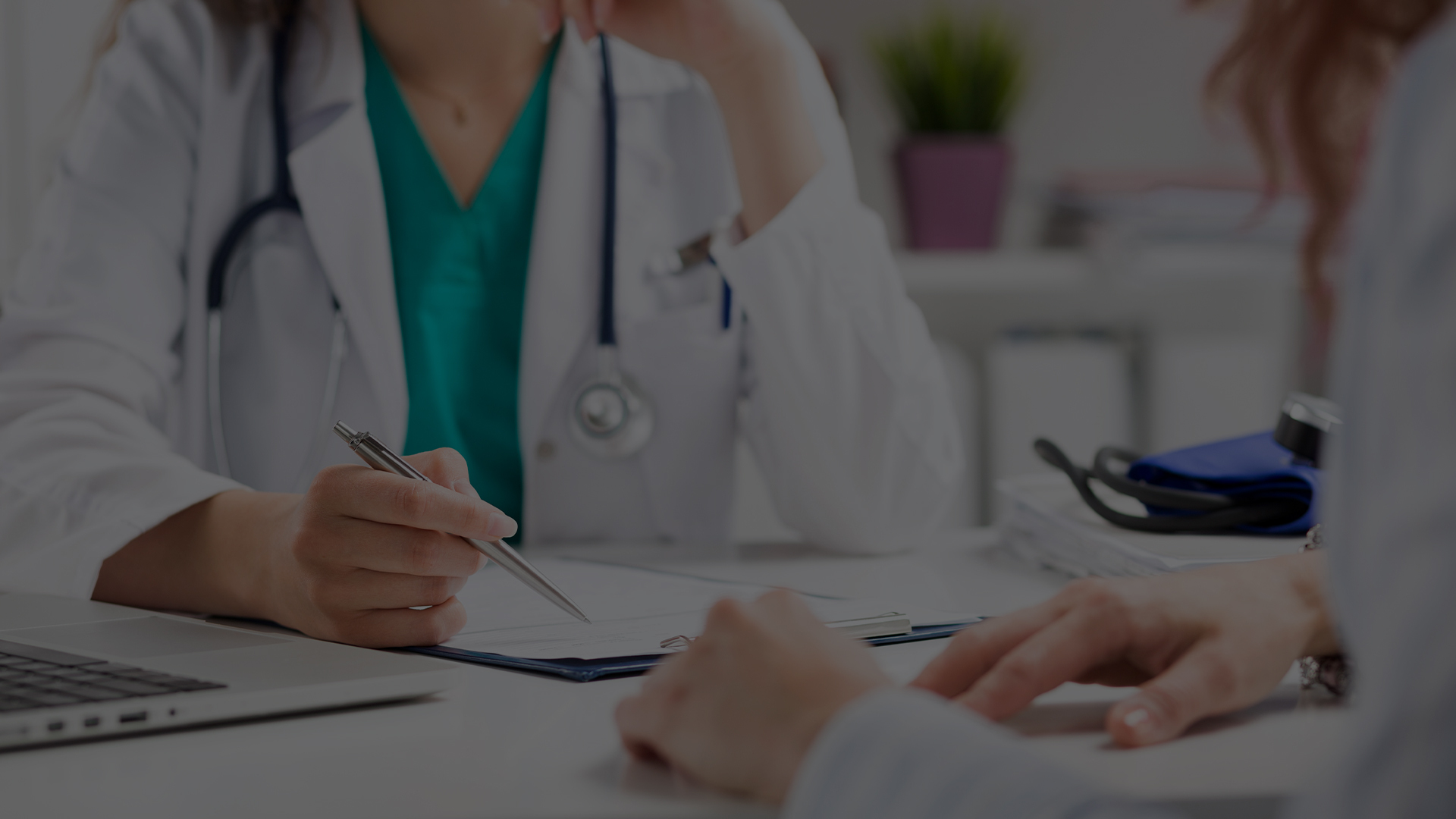 Close up of two people, one a doctor, talking while the doctor takes notes. 