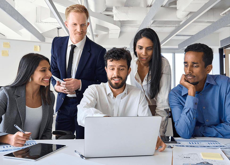 Several employees crowd around a computer, looking at the screen and interacting 