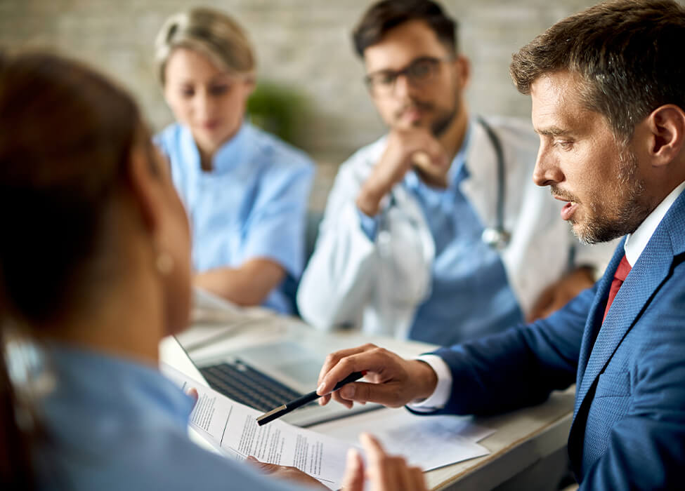 A healthcare team, including a doctor, discussing strategies to streamline open enrollment for better member engagement and efficient processing.