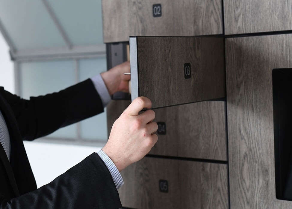 Businessman using smart lockers for offices, securely accessing a locker with a digital keypad in a contemporary office setting.